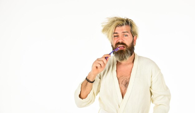 Zdjęcie poranna rutyna higiena jamy ustnej mężczyzna w szlafroku trzyma szczoteczkę do zębów higiena osobista brodaty hipster czyszczenie zębów świeżość i czystość utrzymuj zdrowe zęby zdrowe nawyki myj zęby