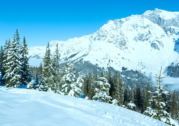 Poranny zimowy krajobraz górski z chmurami w dolinie (region Hochkoenig, Austria)