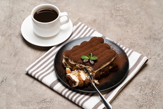 porcja deseru Classic tiramisu i filiżankę świeżej kawy espresso na betonowym tle