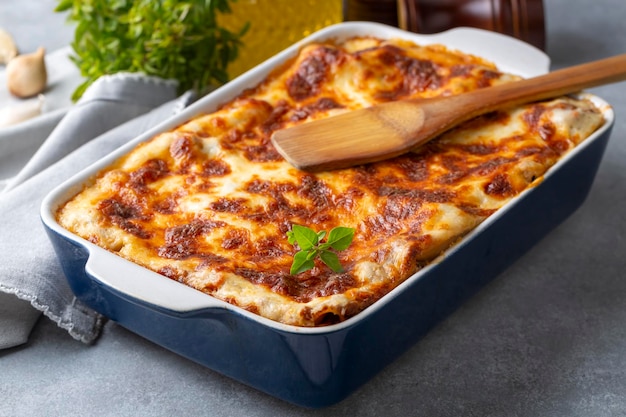 Porcja lasagny z mielonej wołowiny z roztopionym serem i świeżą pietruszką podawana na talerzu na widok z bliska do menu