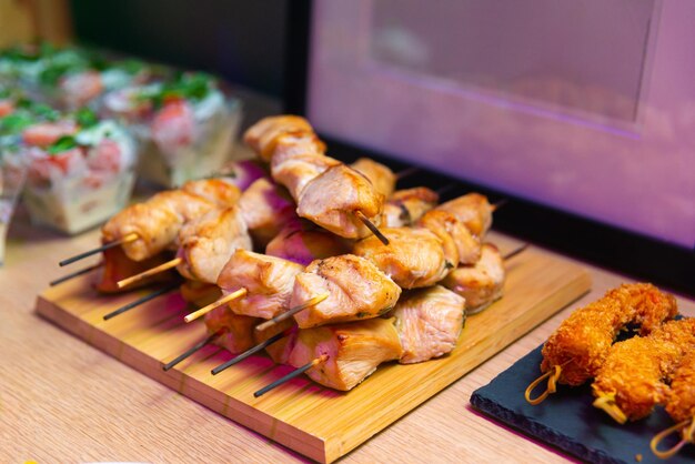 Porcje mięsa z piersi kurczaka na szaszłykach na drewnianej desce jako przekąska imprezowa