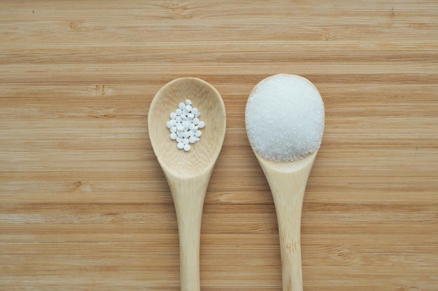 Porównanie słodzika Sugar Substitute i surowego cukru na drewnianej łyżce
