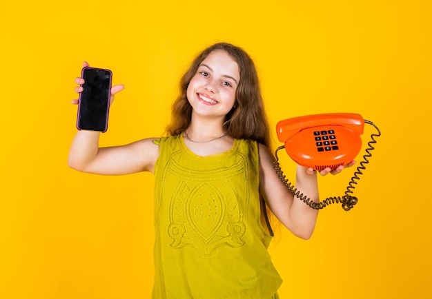 Porozmawiaj z przyjacielem nowoczesne życie koncepcja komunikacji nowej technologii urządzenie vintage moda mała dziewczynka ze smartfonem i telefonem małe dziecko ma rozmowę telefoniczną w stylu retro
