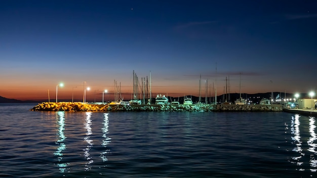 Port morski w nocy na wybrzeżu Morza Egejskiego z wieloma zacumowanymi łodziami, latarniami w Grecji