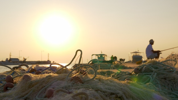 Port z rybakiem i sieciami rybackimi na scenie zachodu słońca na molo