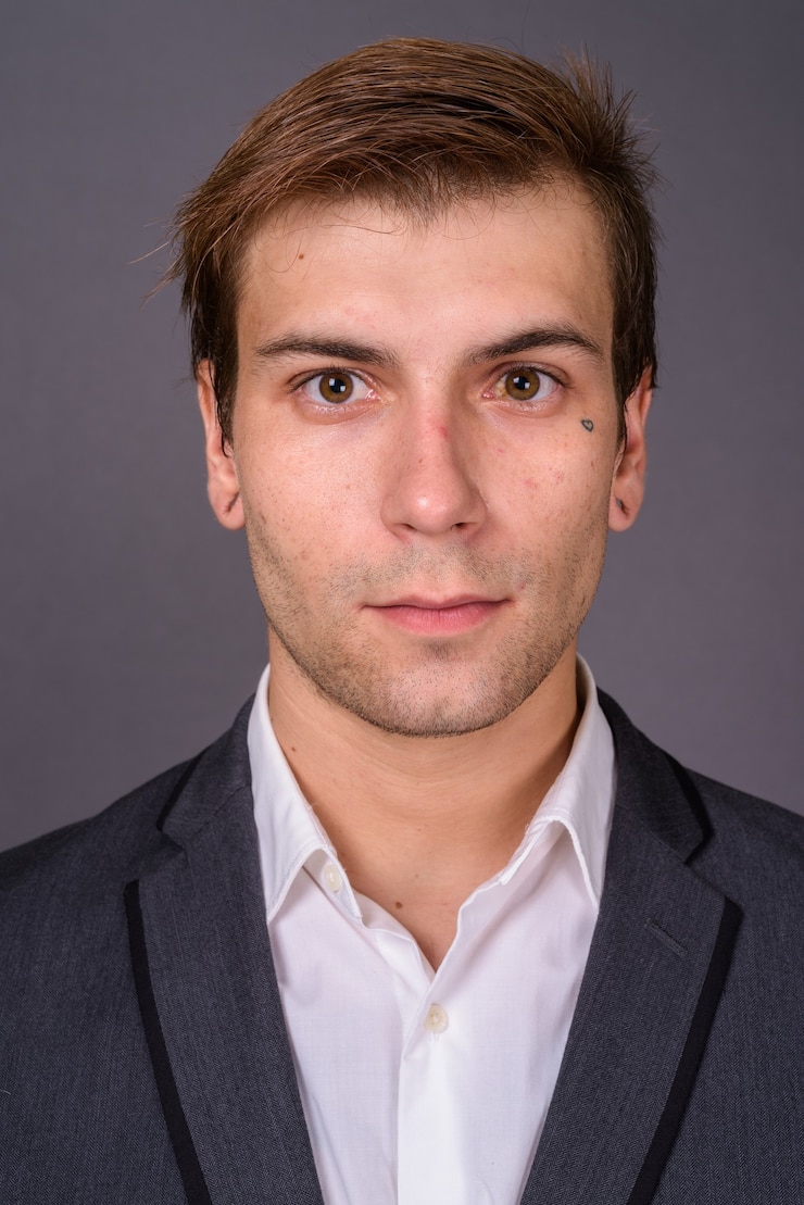 Zdjęcie portait młody przystojny biznesmen przeciw szarej ścianie