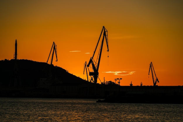 Portowe dźwigi stoczniowe na tle pomarańczowego nieba Ferrol Galicia Hiszpania