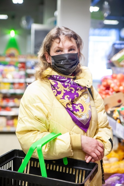 Portret 45-letniej kobiety między półkami z zakupami w supermarkecie