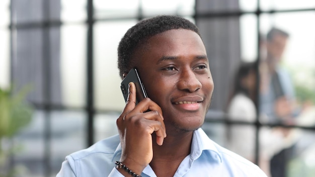 Portret African American biznesmen w biurze z telefonem komórkowym mówiąc rozmawia kryty