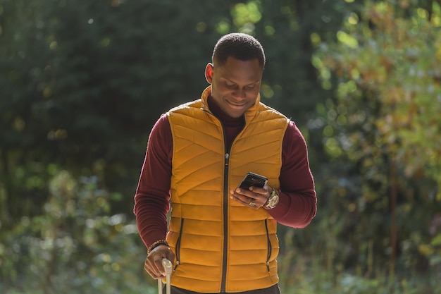 Portret afroamerykanina stojącego z walizką i używającego telefonu komórkowego z aplikacją do taksówki podróżnej wezwania taksówki i koncepcji podróży