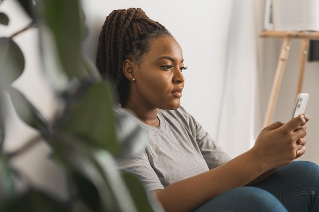 Portret afroamerykańskiej studentki ubranej swobodnie, trzymającej telefon komórkowy i piszącej na maszynie