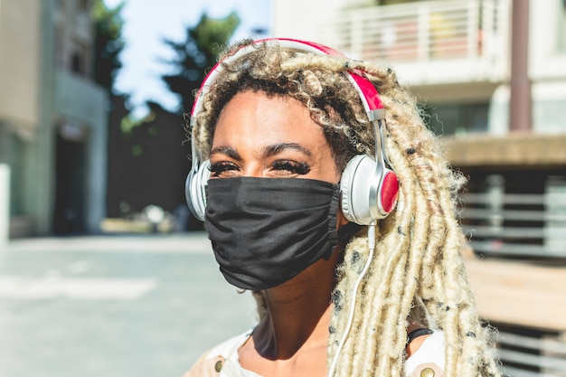 Portret Afrykańskiej Dziewczyny Rusza Się Blond Dreadlocks Słucha Włosianą Muzykę Podczas Gdy Będący Ubranym Twarzy Ochronną Maskę Dla Coronavirus Zapobiegania