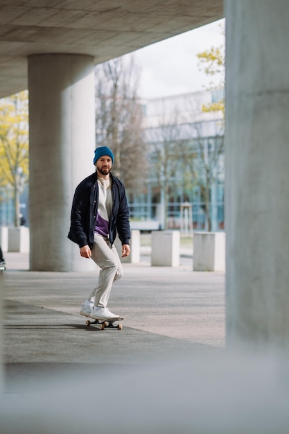 Portret aktywnego deskorolkarza balansującego na deskorolce na tle miejskim Skupiony skater