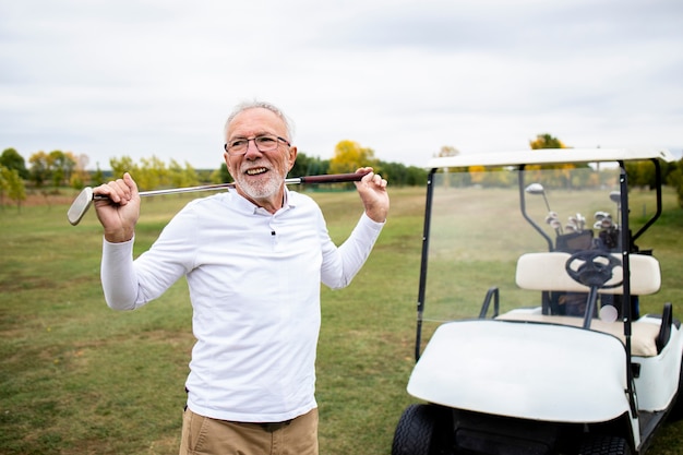 Portret aktywnego starszego mężczyzny, grając w golfa na polu golfowym i ciesząc się wolnym czasem na świeżym powietrzu.