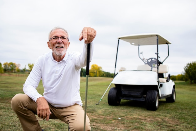 Portret aktywnego starszego mężczyzny, grając w golfa na polu golfowym i ciesząc się wolnym czasem na świeżym powietrzu.