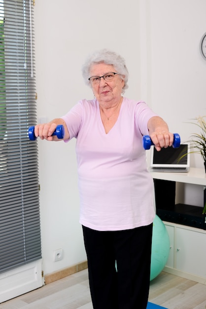 Portret aktywnej i dynamicznej starszej kobiety uprawiającej sport fitness w domu