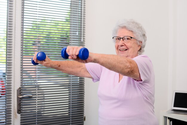 Portret aktywnej i dynamicznej starszej kobiety uprawiającej sport fitness w domu