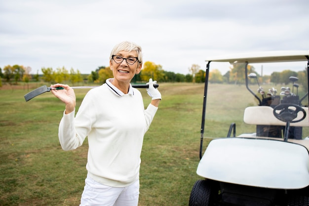 Portret aktywnej starszej kobiety, grając w golfa na polu golfowym i ciesząc się wolnym czasem na świeżym powietrzu.