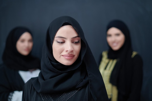 Portret arabskich kobiet noszących tradycyjne stroje lub abaya. Młode muzułmańskie dziewczyny pozujące przed czarną tablicą reprezentującą islamską arabską modę i koncepcję ramadan kareem