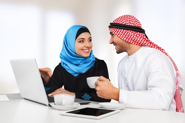 Portret arabskiej pary z laptopem na tle