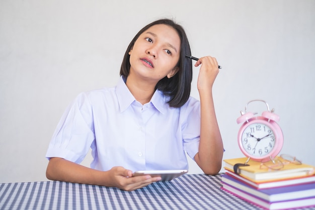 Portret Asian młoda dziewczyna siedzi z książką i białym landscapein mundurze studenta