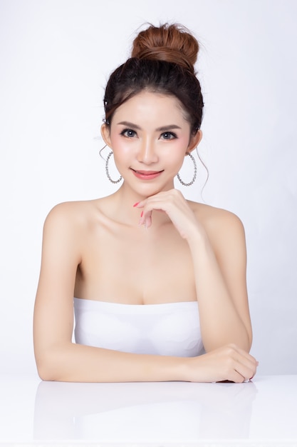 Zdjęcie portret atrakcyjna azjatykcia kobieta siedzi ono uśmiecha się na białym tle.