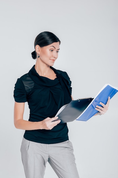 Portret atrakcyjne kobiety biznesu trzyma folder z dokumentami na szarym tle