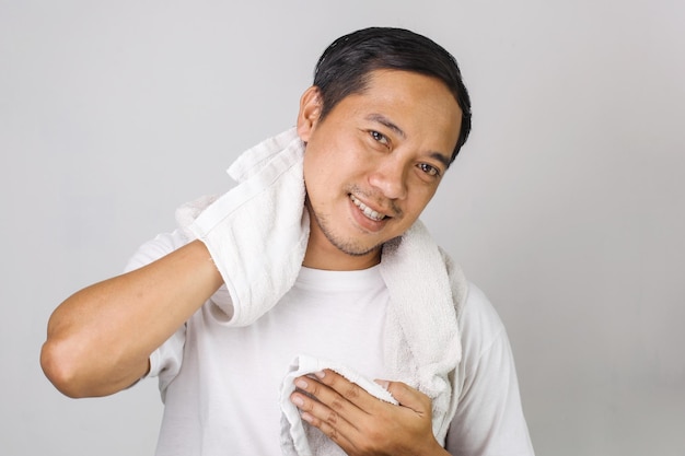 Portret atrakcyjnego azjatyckiego mężczyzny wycierającego twarz ręcznikiem po zwilżeniu peelingu