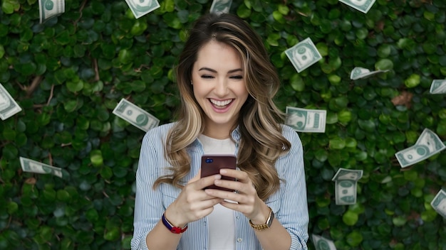 Portret atrakcyjnej brunetki w wieku trzydziestu lat wygrywającej mnóstwo pieniędzy w dolarach za pomocą swojego smartfo