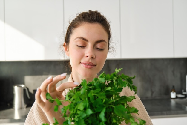 Portret atrakcyjnej dziewczyny z pęczkiem pietruszki jedzącej świeże zioła i warzywa gotowane w