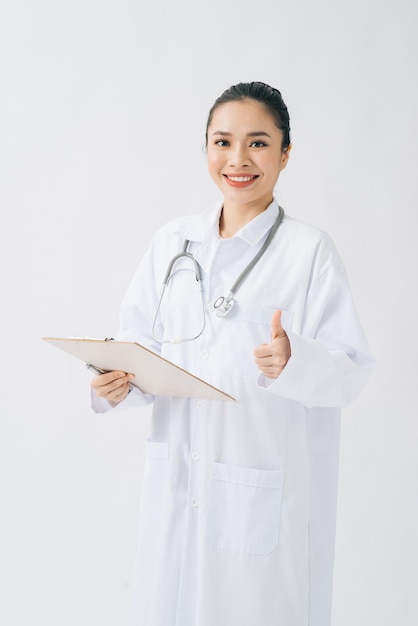Portret atrakcyjnej młodej kobiety lekarza lub pielęgniarki w białym mundurze ze stetoskopem, trzymając dokumenty medyczne