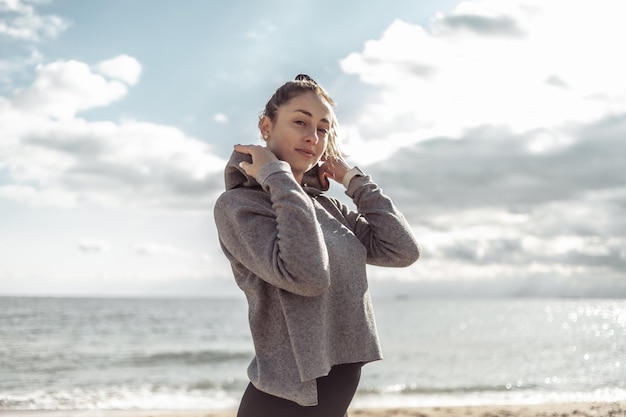 Portret atrakcyjnej szczupłej kobiety w sportowej odzieży na plaży w jasny słoneczny dzień