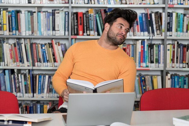 Portret atrakcyjnej uczennicy wykonującej jakąś pracę szkolną z laptopem w bibliotece