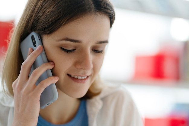 Portret atrakcyjnej uśmiechniętej kobiety trzymającej telefon komórkowy po wezwaniu, selektywna ostrość. Technologia