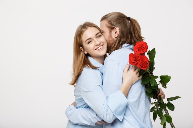 Portret atrakcyjny młody człowiek ukrywa kwiaty od swojej dziewczyny