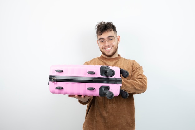 Portret atrakcyjny model mężczyzna stojący i trzymając różową torbę podróżną.