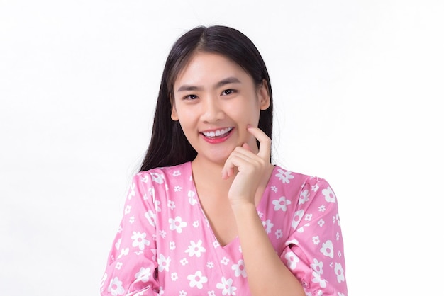 Portret Azjatycka piękna dziewczyna w różowej sukience i czarnych długich włosach Jej dłonie dotykają uśmiechu policzka