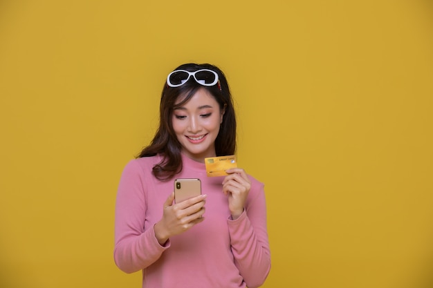Portret Azjatycka piękna szczęśliwa młoda kobieta uśmiecha się wesoło, a ona trzyma kartę kredytową