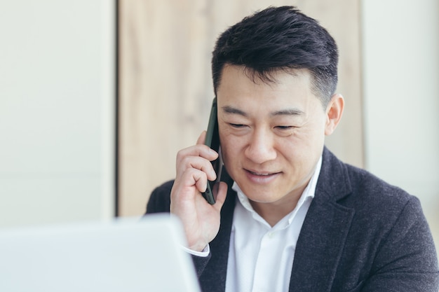 portret azjatyckiego biznesmena udany i szczęśliwy uśmiechnięty rozmawia przez telefon w garniturze