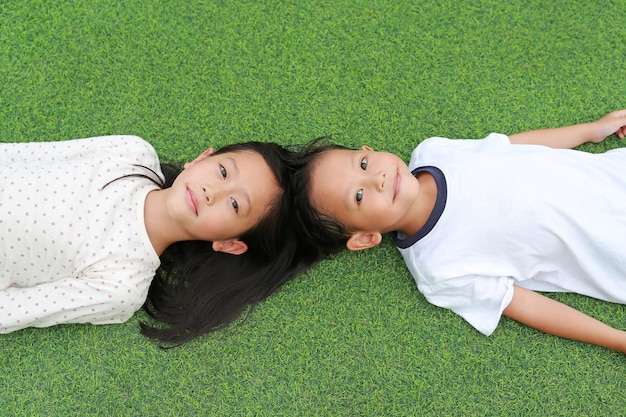 Zdjęcie portret azjatyckiego małego chłopca i dziewczynki dziecko leżące na tle zielonej trawy razem