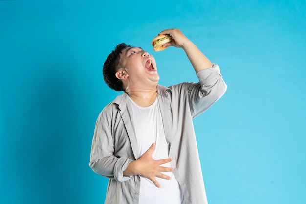 Portret azjatyckiego mężczyzny jedzącego fast food na niebieskim tle