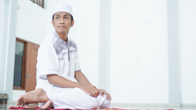 Portret azjatyckiego muzułmanina modlącego się w meczecie, imię modlitwy to sholat, co dotyczy końca sholat