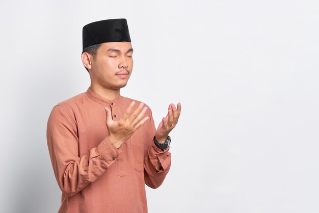 Portret azjatyckiego muzułmanina modlącego się z otwartym ramieniem na białym tle na białym tle