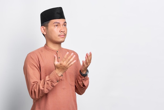 Portret azjatyckiego muzułmanina modlącego się z otwartym ramieniem na białym tle na białym tle