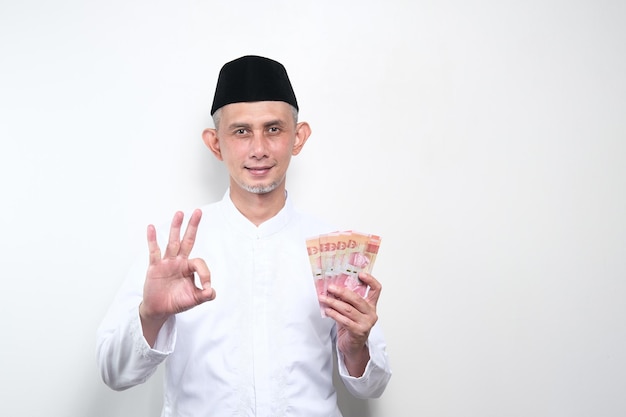 Portret azjatyckiego muzułmanina trzymającego w ręku dużo pieniędzy, pojęcie oszczędzania, inwestowania
