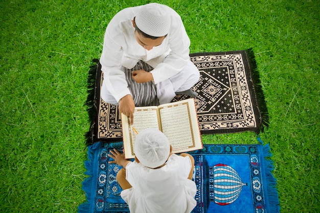 Portret azjatyckiego muzułmańskiego ojca uczącego syna czytać koran