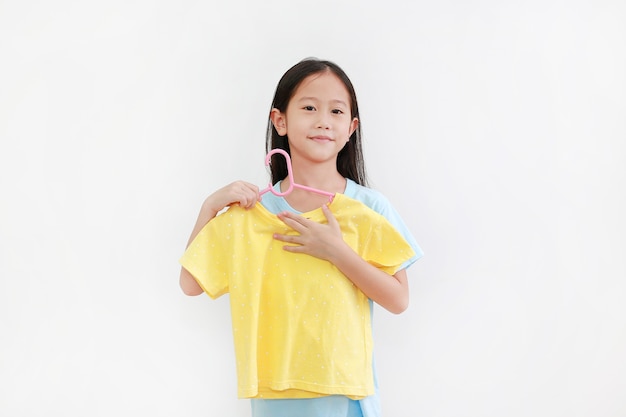 Portret azjatyckiej małej dziewczynki próbującej żółtej koszuli na białym tle