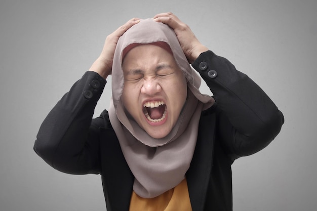 Portret azjatyckiej muzułmanki w hidżabie pokazuje gniewny krzyk, gest, stres, depresja
