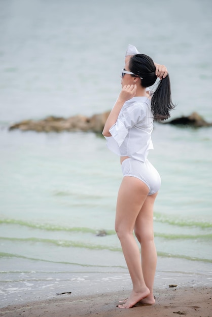 Portret azjatyckiej pięknej seksownej kobiety nosi bikini nad morzem o zachodzie słońcaZrelaksuj sięKoncepcja letniej plaży