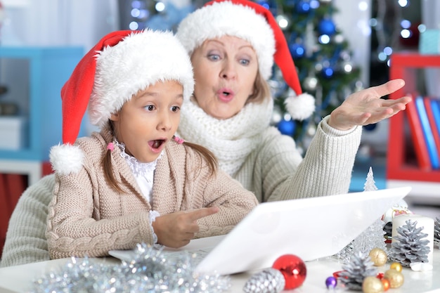 Portret babci i wnuczki korzystających z laptopa w Boże Narodzenie w domu